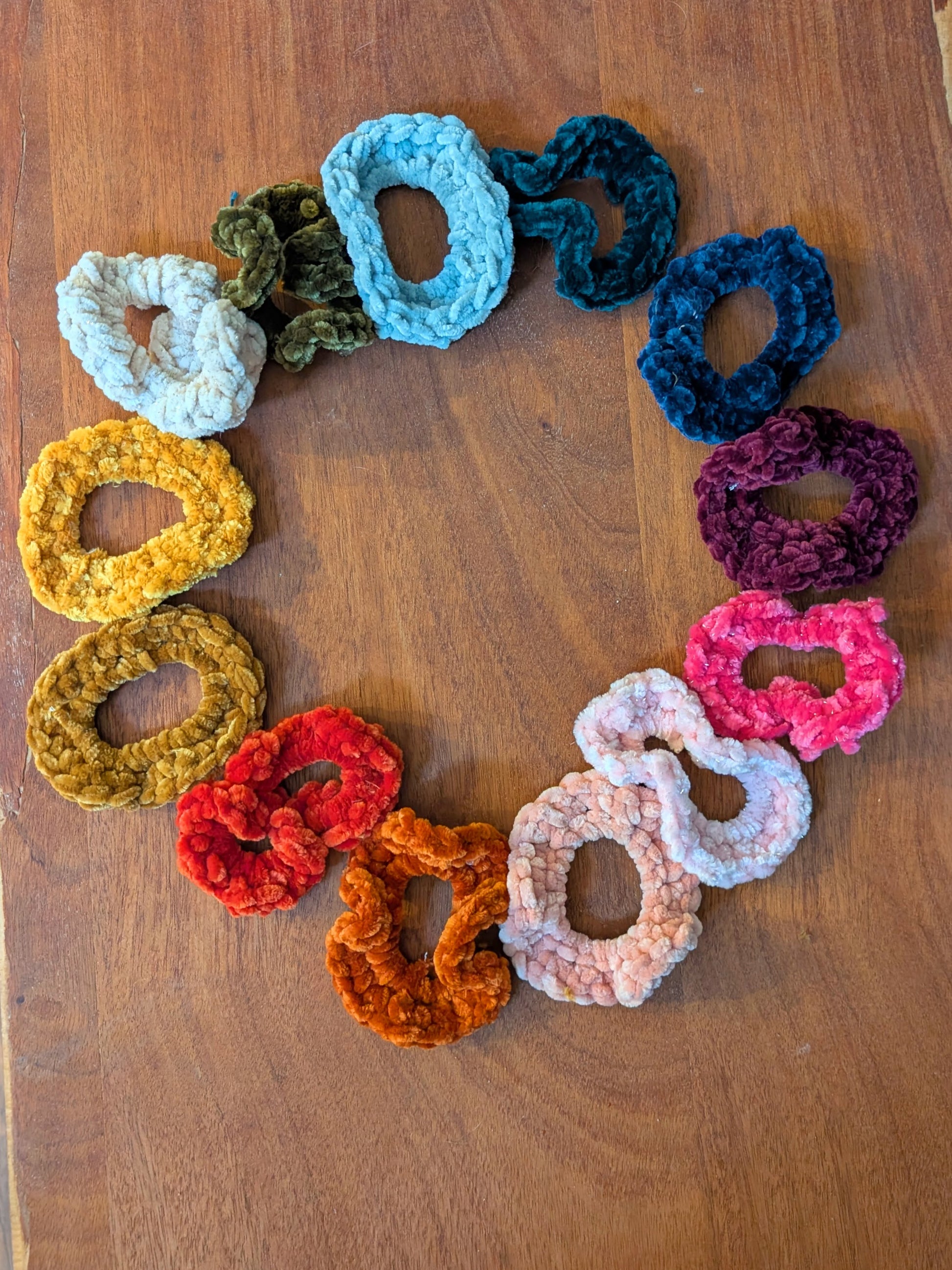 Colorful crocheted scrunchies on a wooden surface