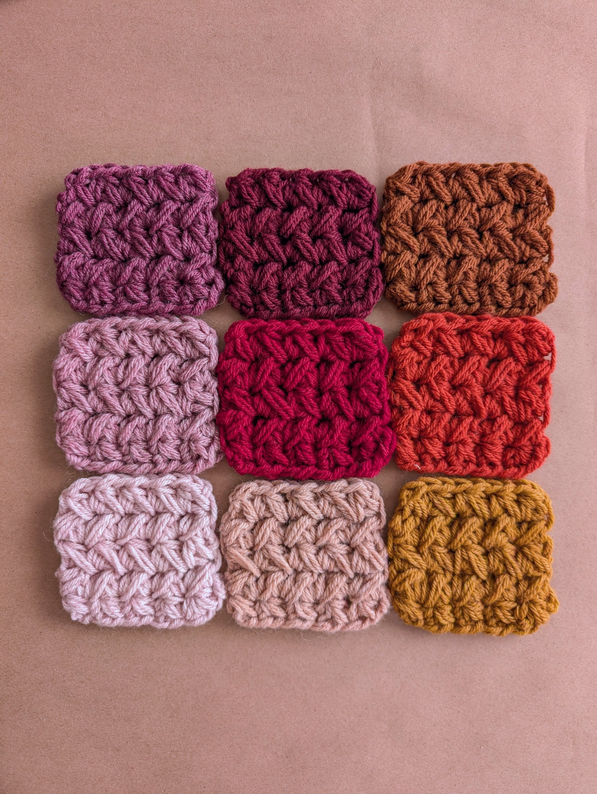 Nine crocheted squares in various colors arranged in a 3x3 grid on a beige background.