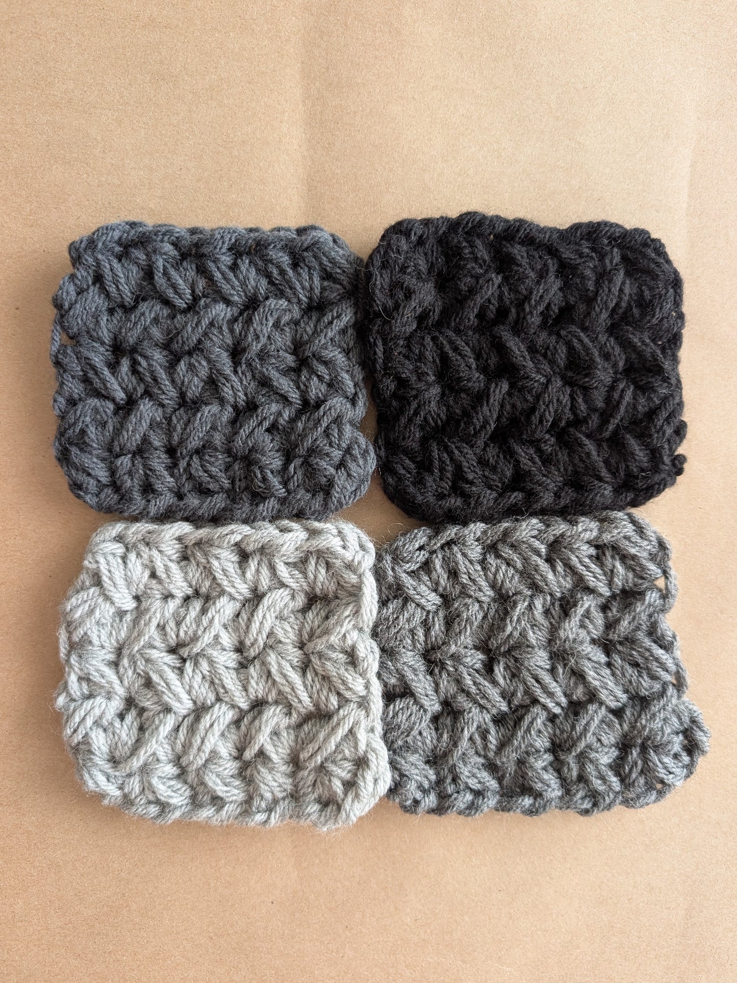 Four crocheted squares in black, dark gray, and light gray on a beige background