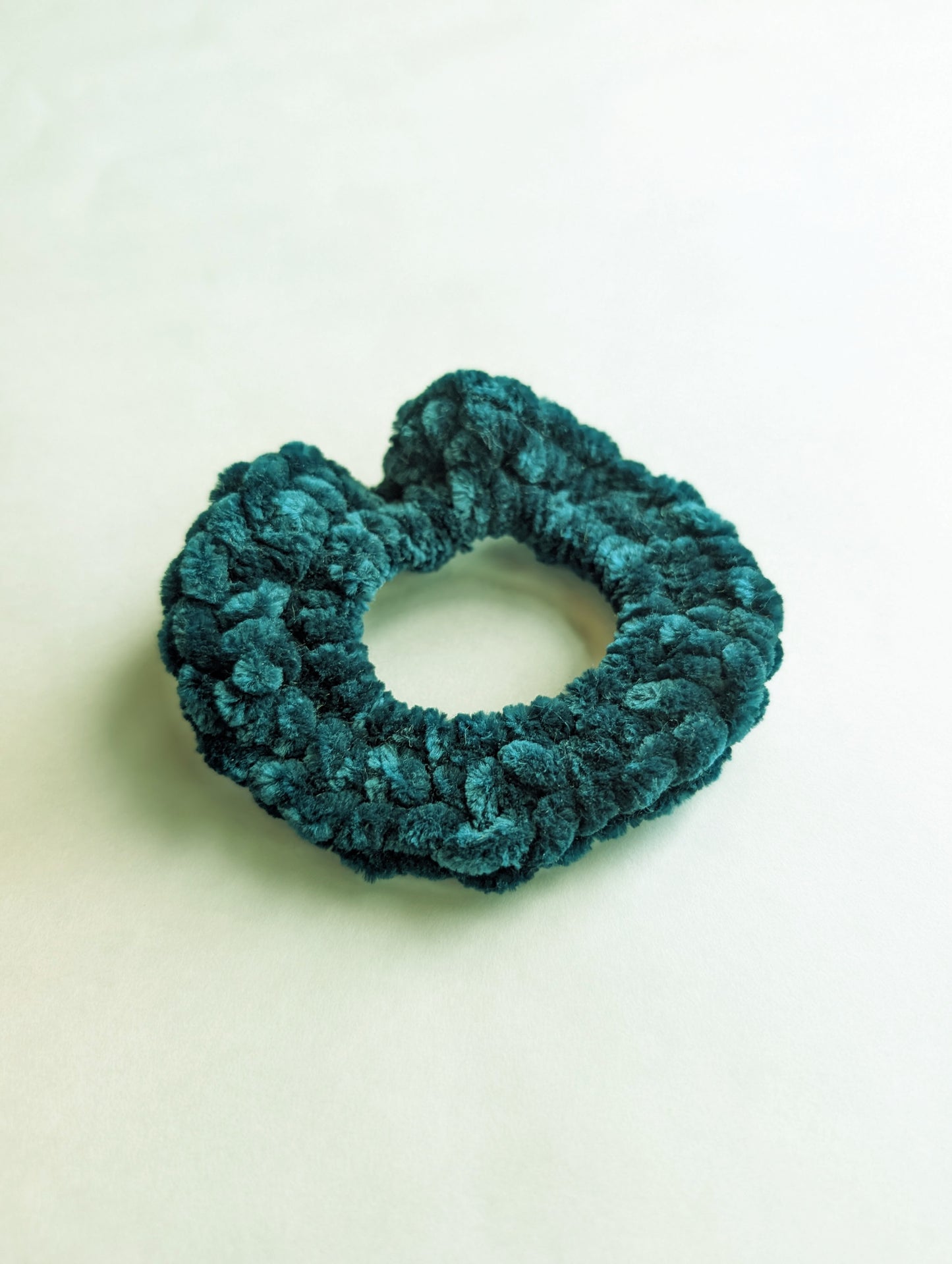 Teal scrunchie on a light beige background