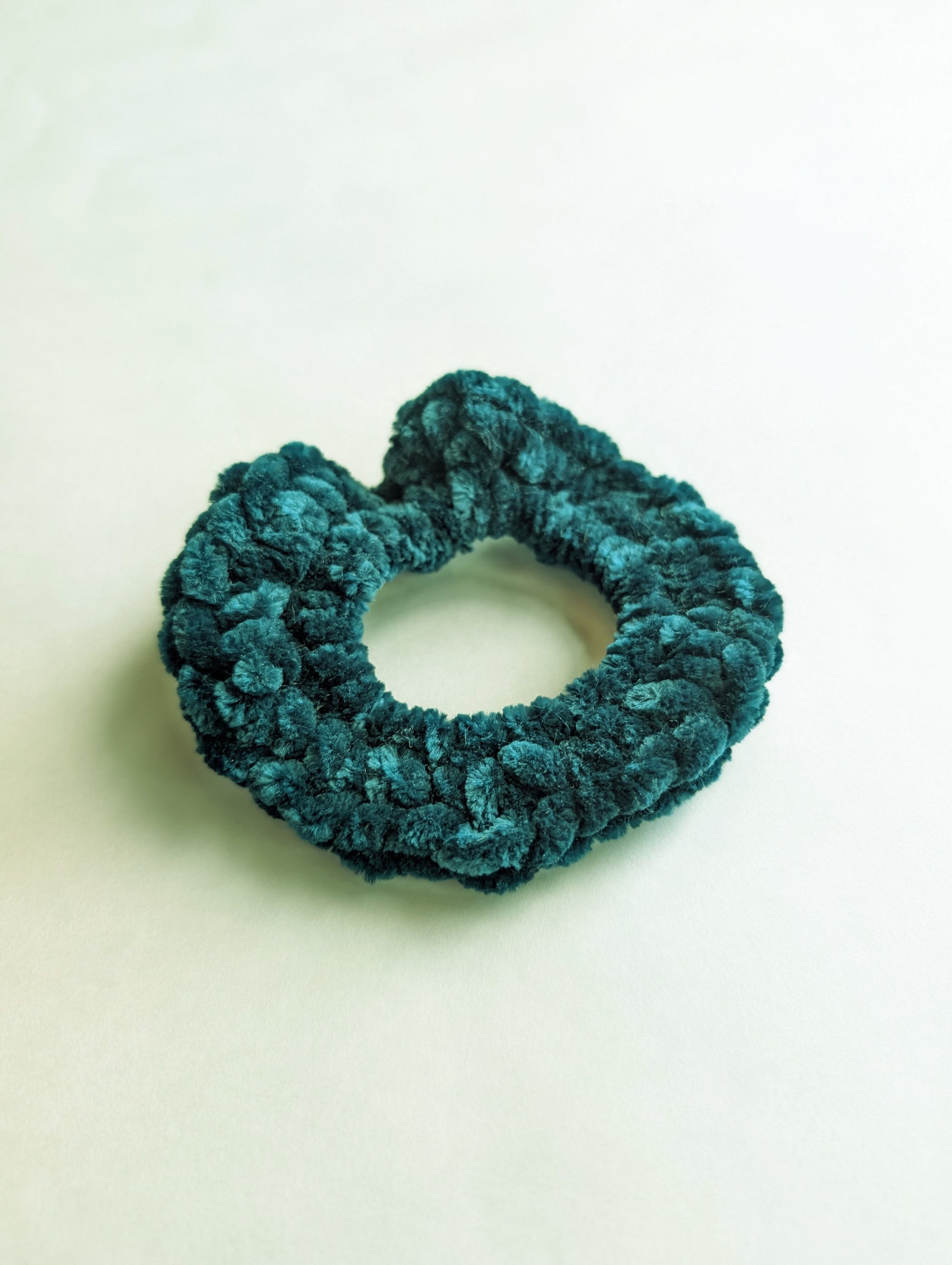 Teal scrunchie on a light beige background