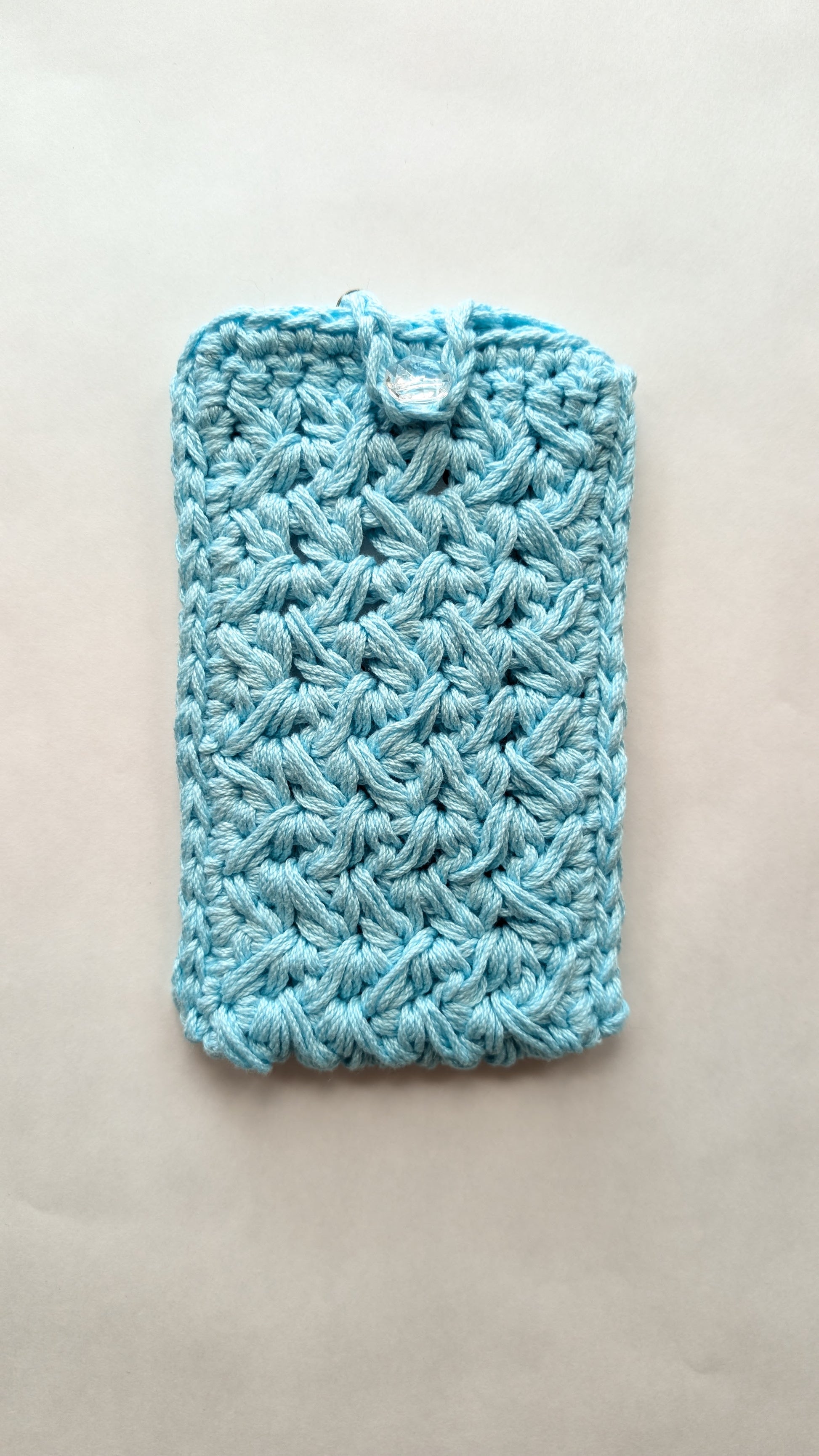 Blue crocheted pouch on a beige background