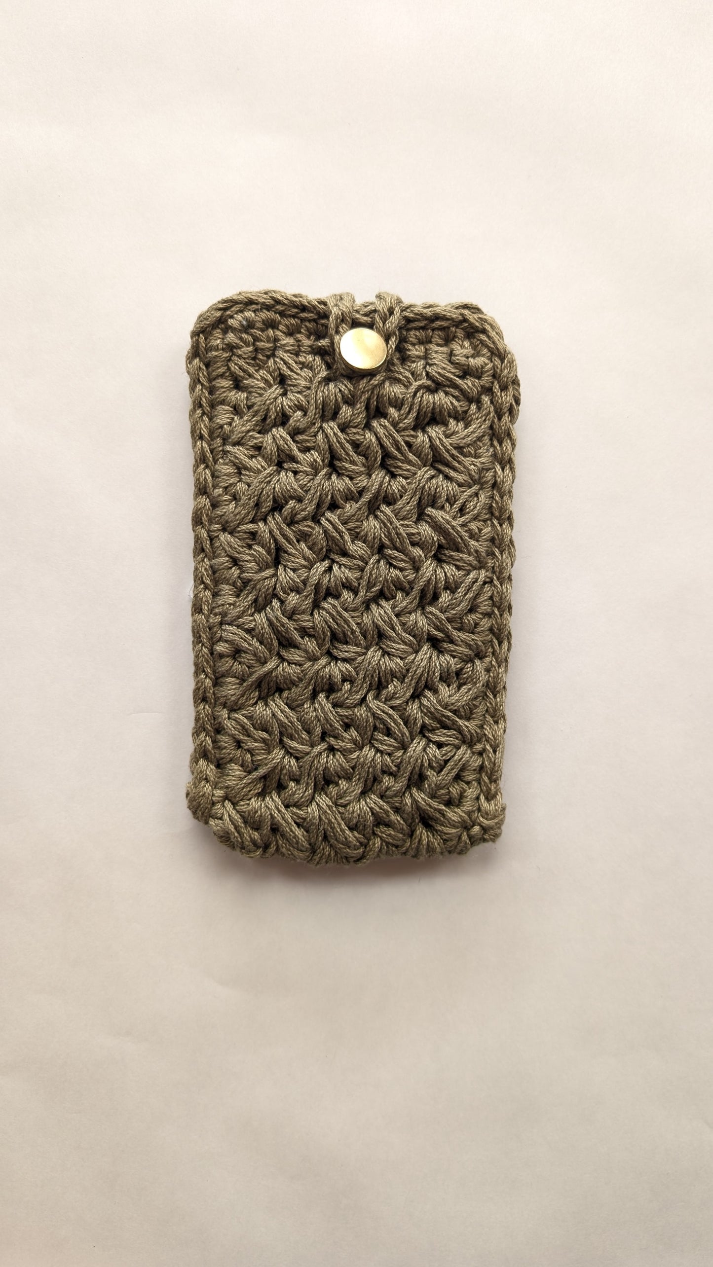Green crocheted phone case on a light beige background
