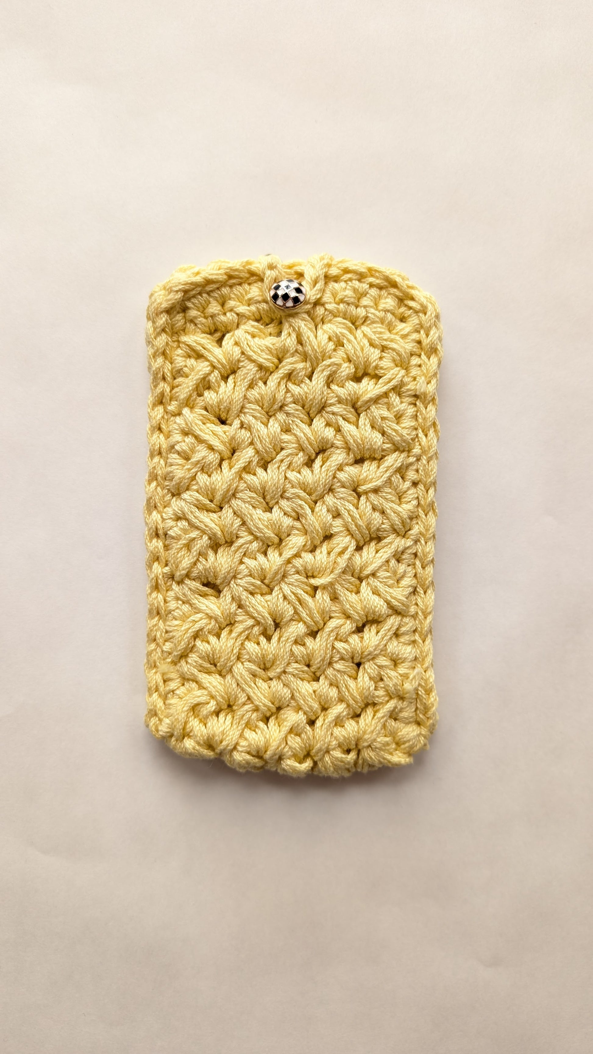 Yellow crocheted phone case on a beige background